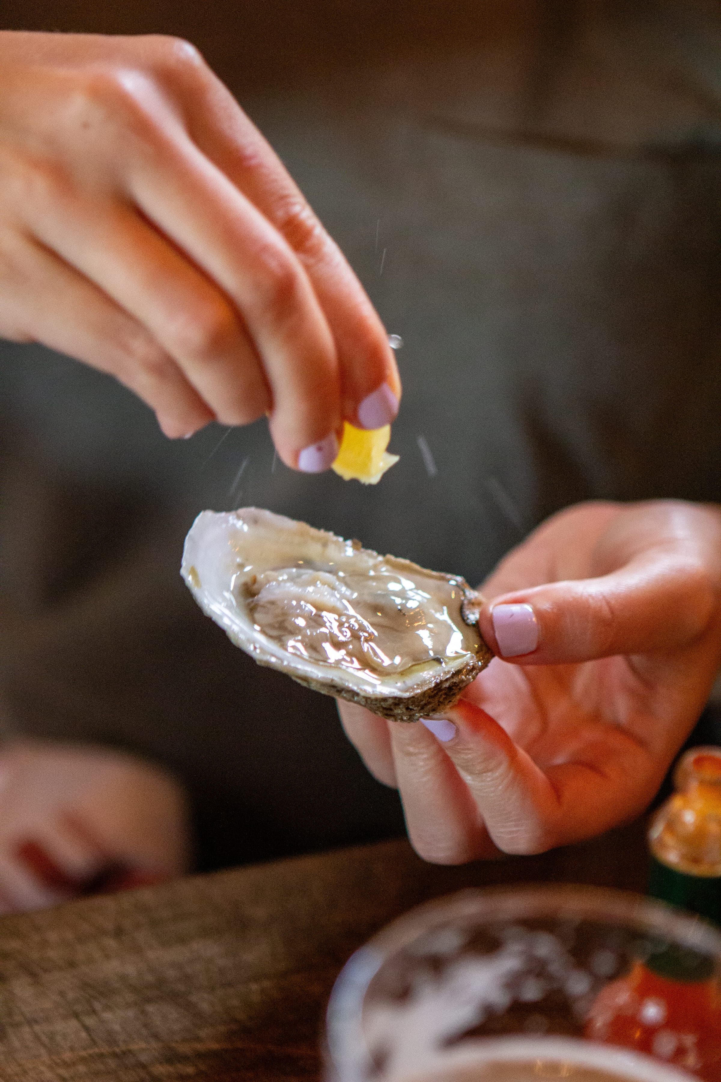 A guest squeezing lemon over a fresh oyster at happy hour in Berwyn PA